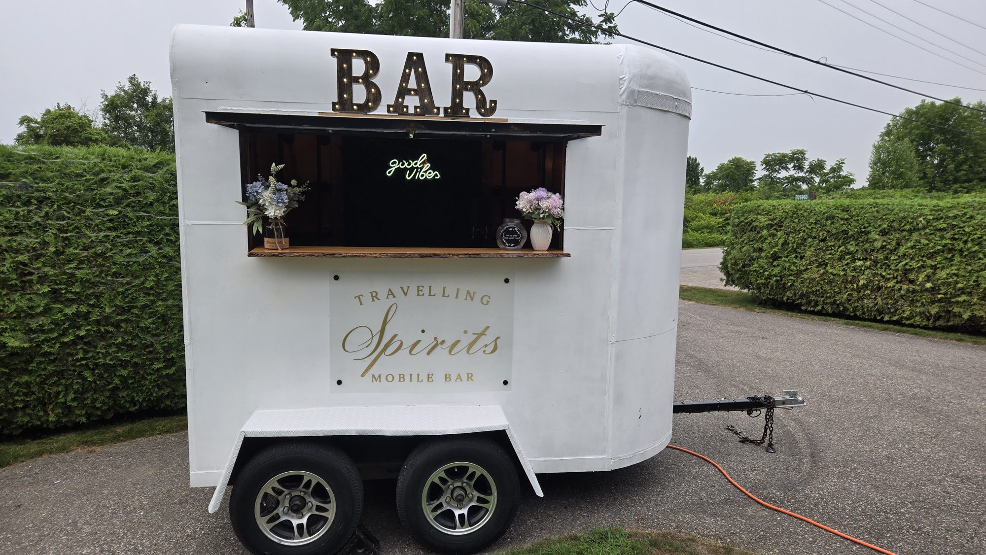 Vintage white mobile bar trailer with illuminated BAR marquee sign parked outdoors for an Ontario event